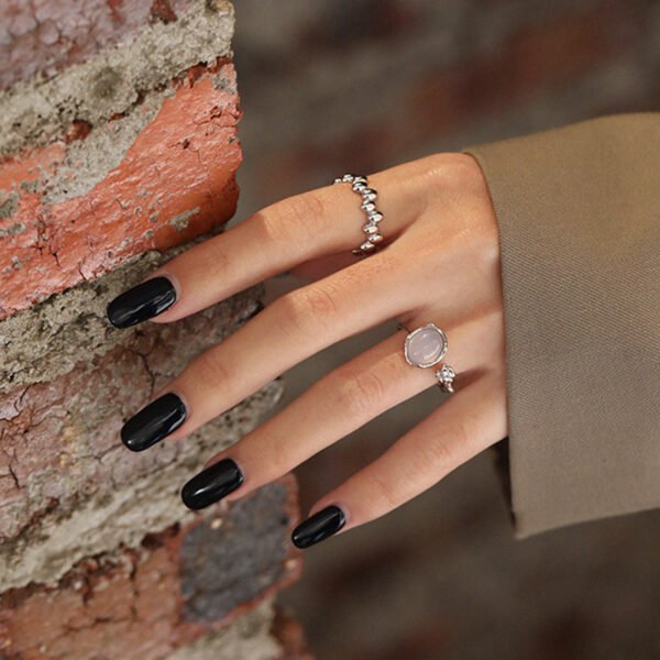 a hand with black nails and sterling silver rings